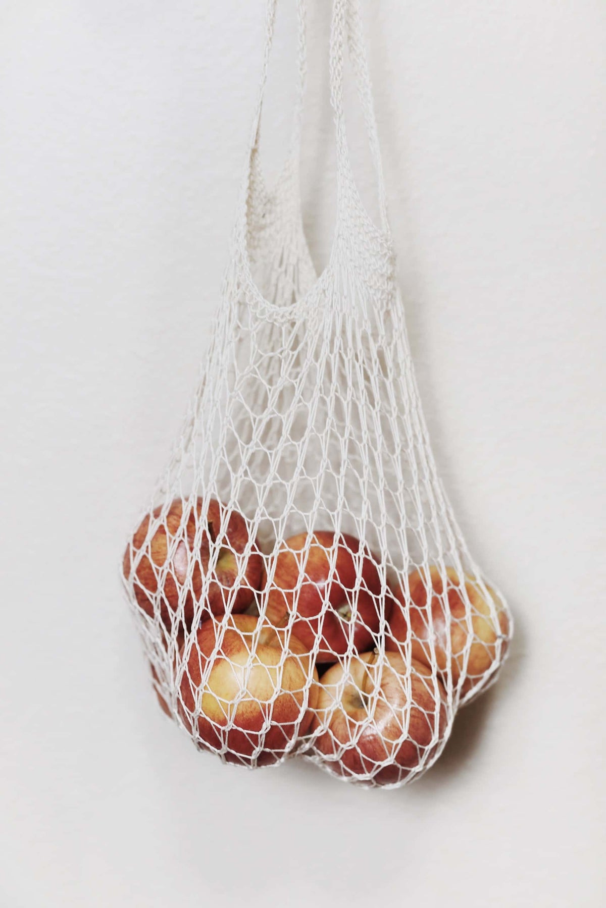 Knitted mesh produce bag holding fresh produce showing stretchy lightweight design