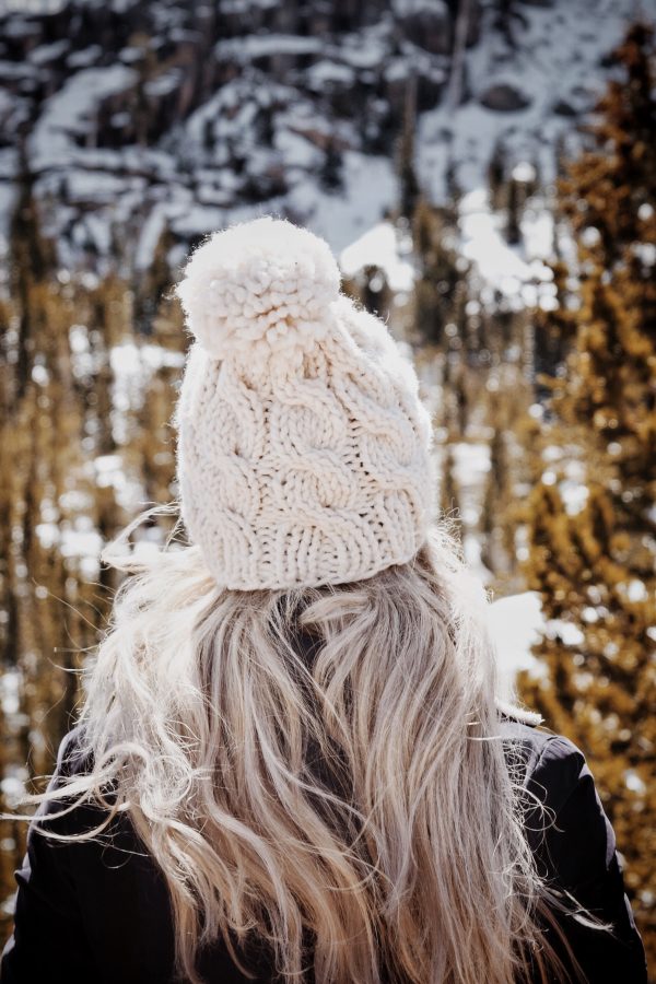 Woman wearing cream cable beanie knitting pattern with cozy winter sweater