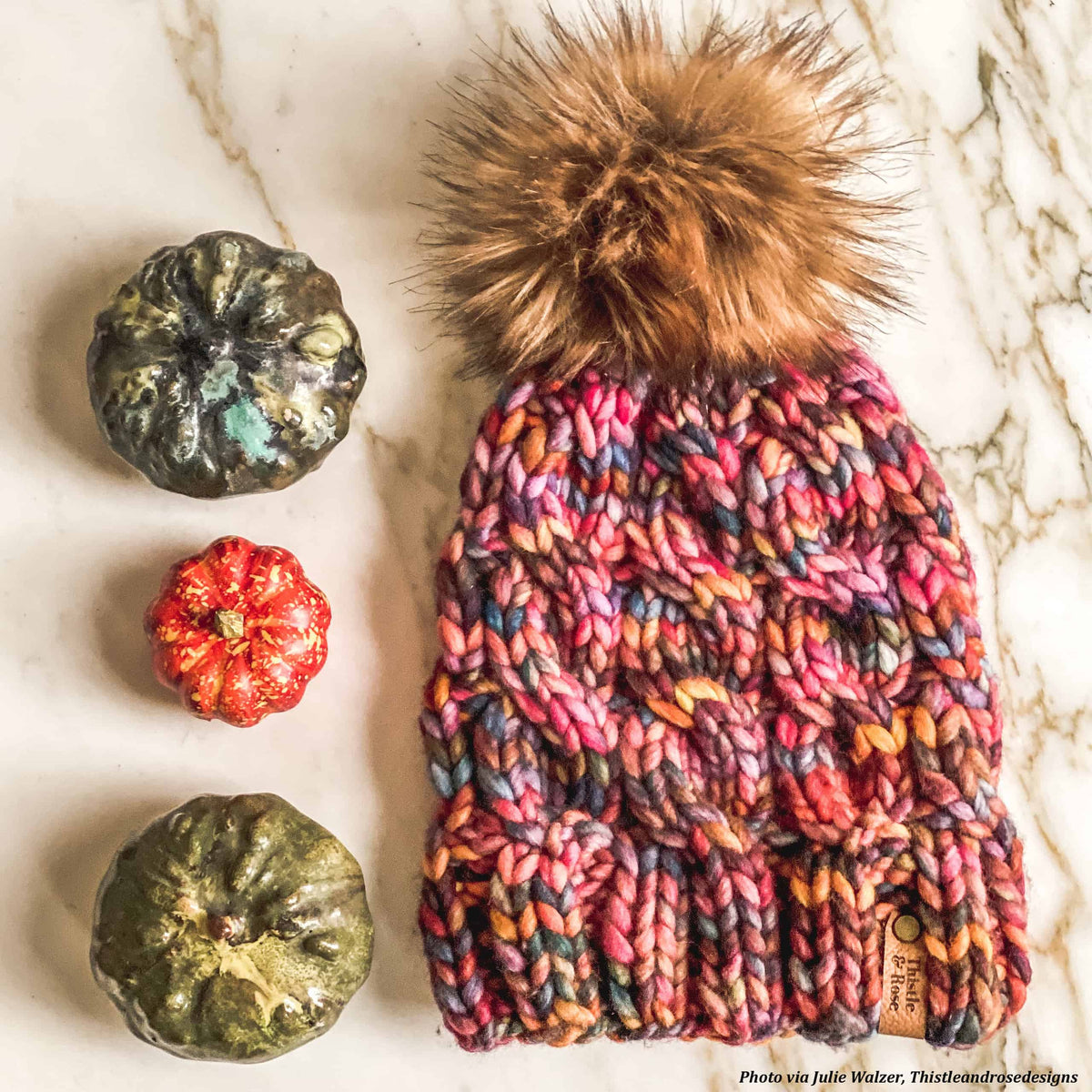 Cream chunky cable beanie with pom pom styled on rustic wooden surface
