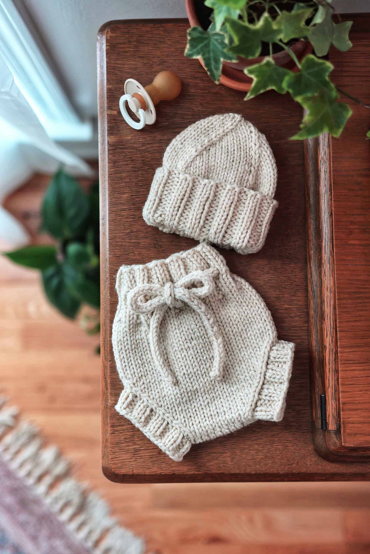 Handknit baby bloomers and beanie set in soft cream yarn on white background