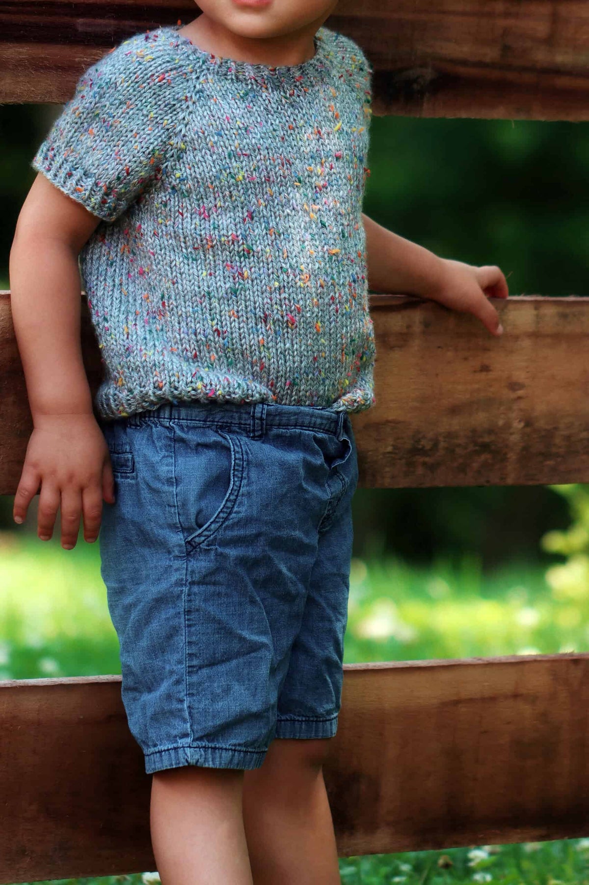 Baby wearing handknit cream tee shirt sweater from top down raglan pattern
