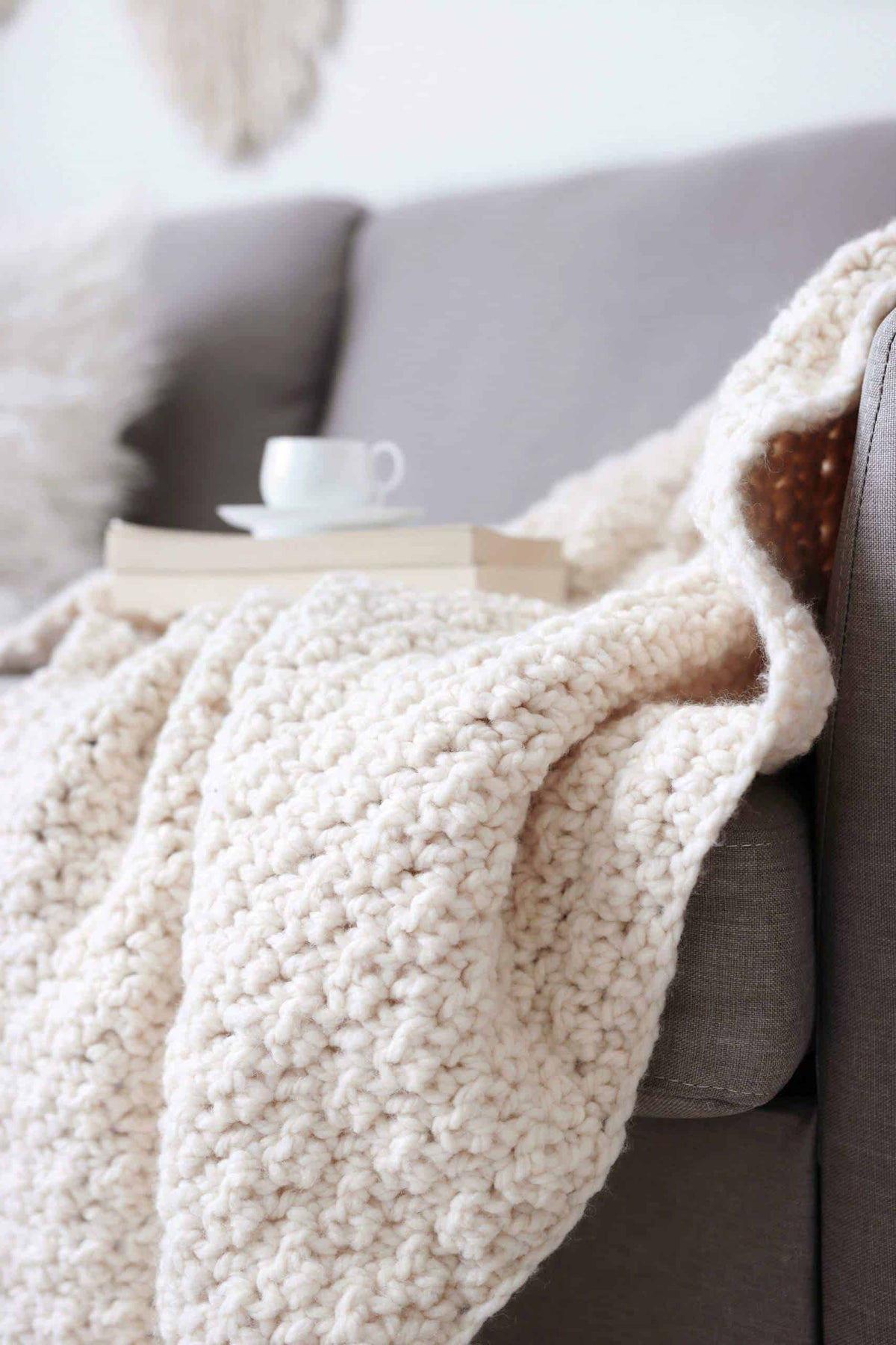 Beginner crochet throw blanket pattern draped over furniture in neutral home