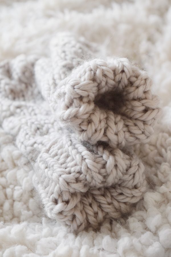 Pair of handknit cable mittens in neutral cream yarn with ribbed wrist detail