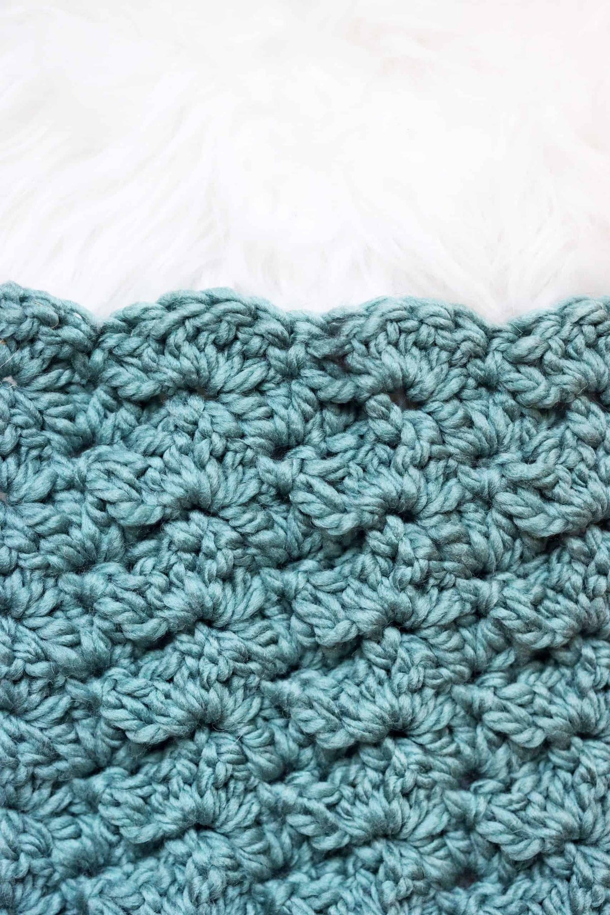 Close-up of Alluvial throw crochet pattern showing textured scallop stitch detail in cream yarn
