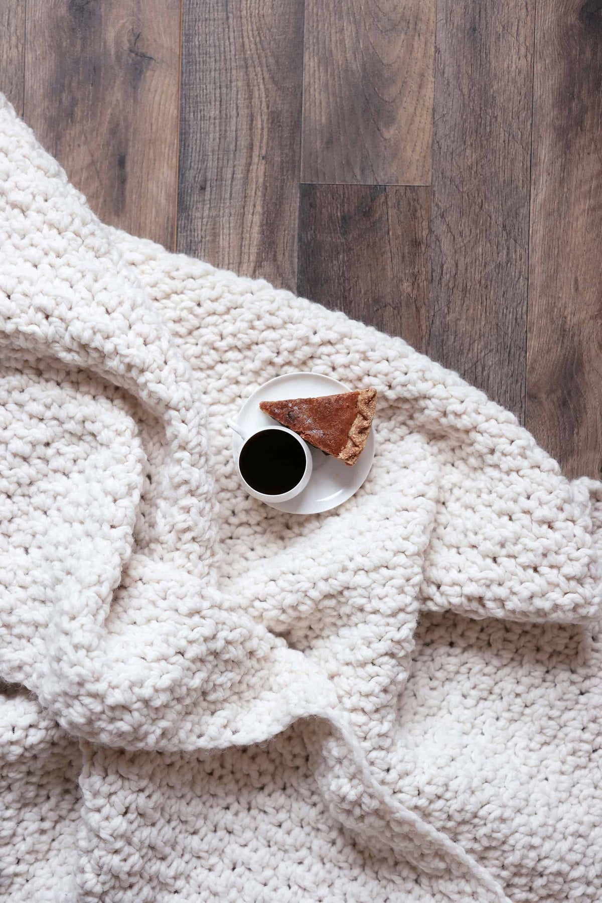 Beginner friendly chunky crochet blanket pattern folded on wooden surface