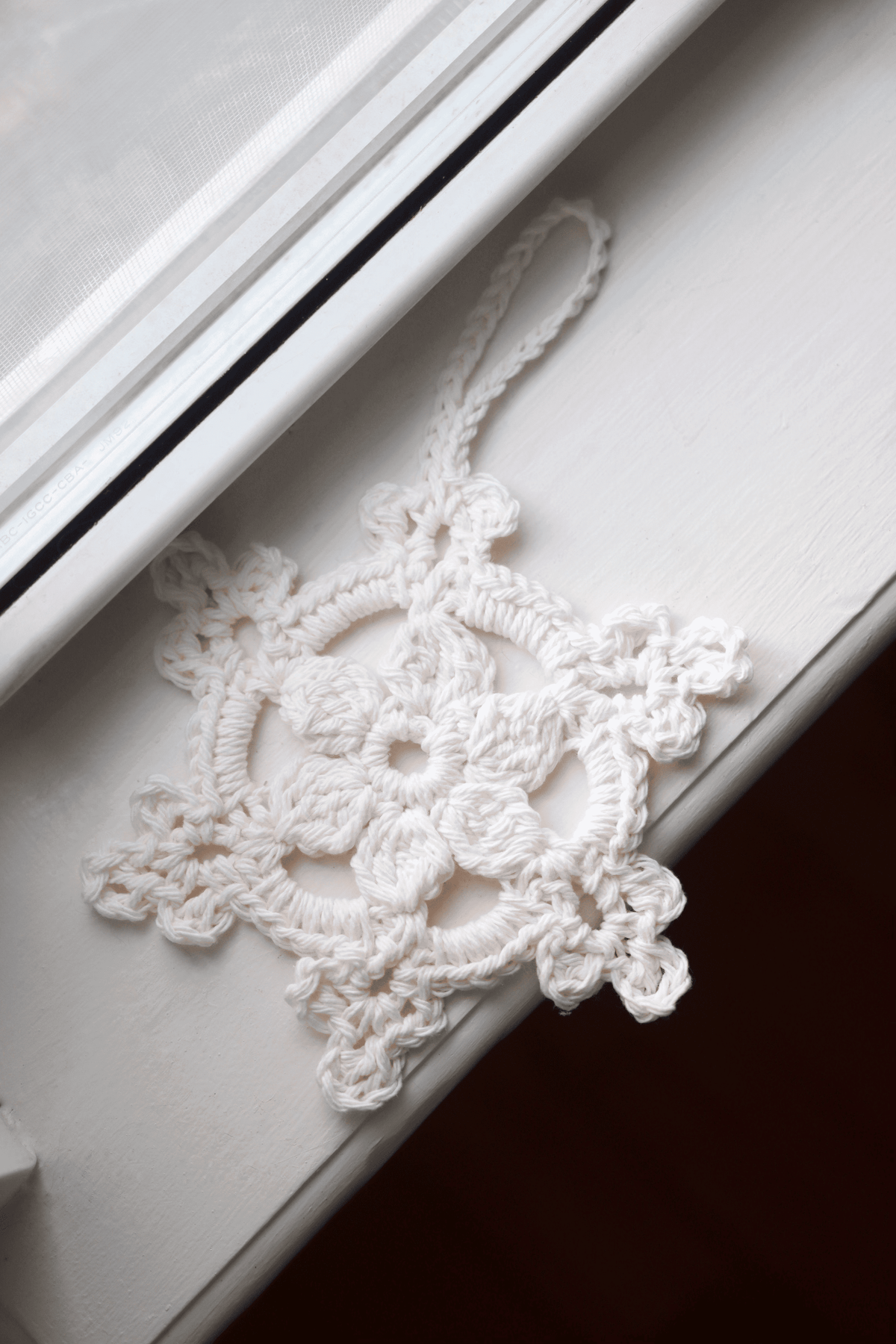 The Snowflake Ornament crochet pattern cover showing finished white snowflake design