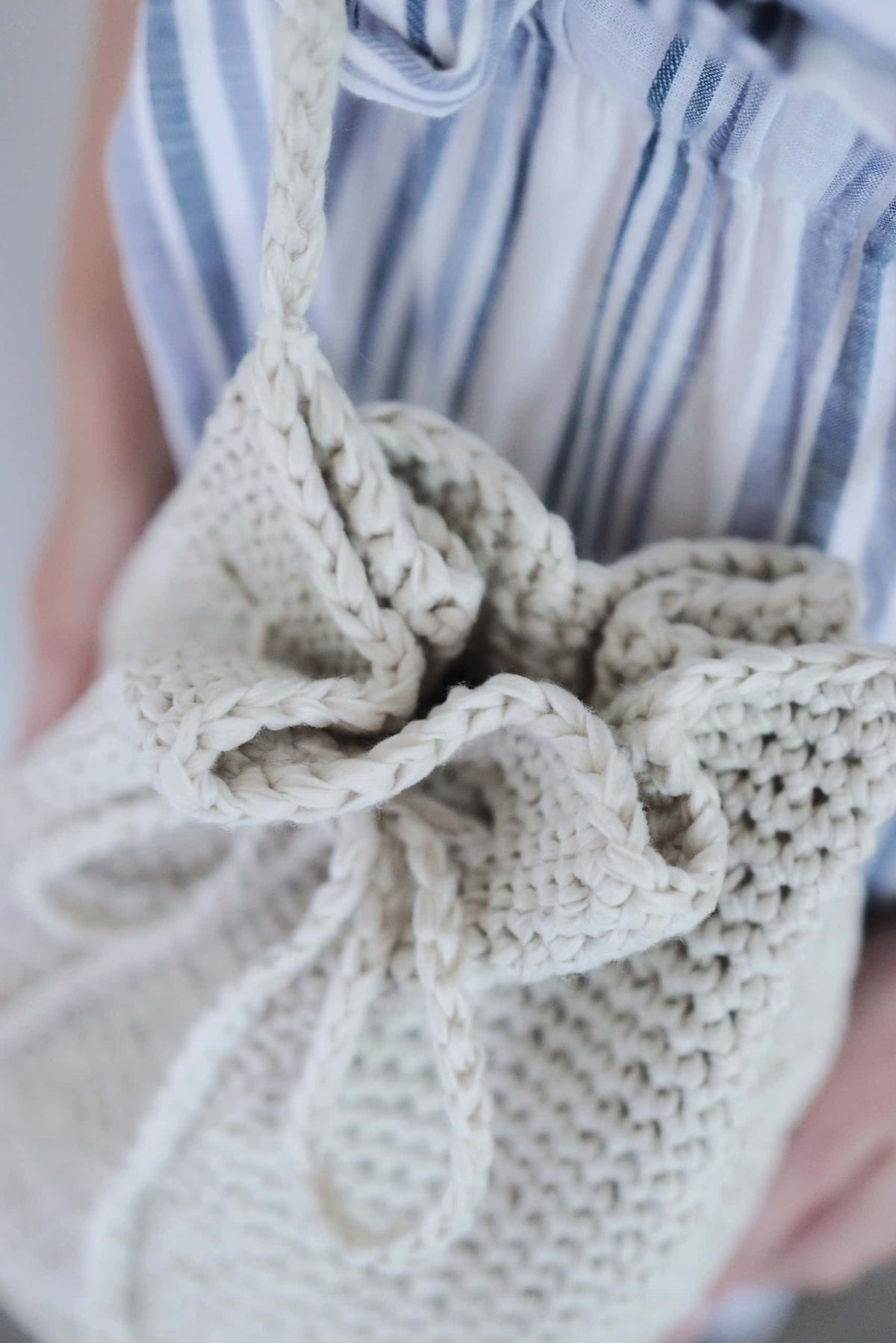 Drawstring bucket bag crochet pattern in neutral cream showing functional closure