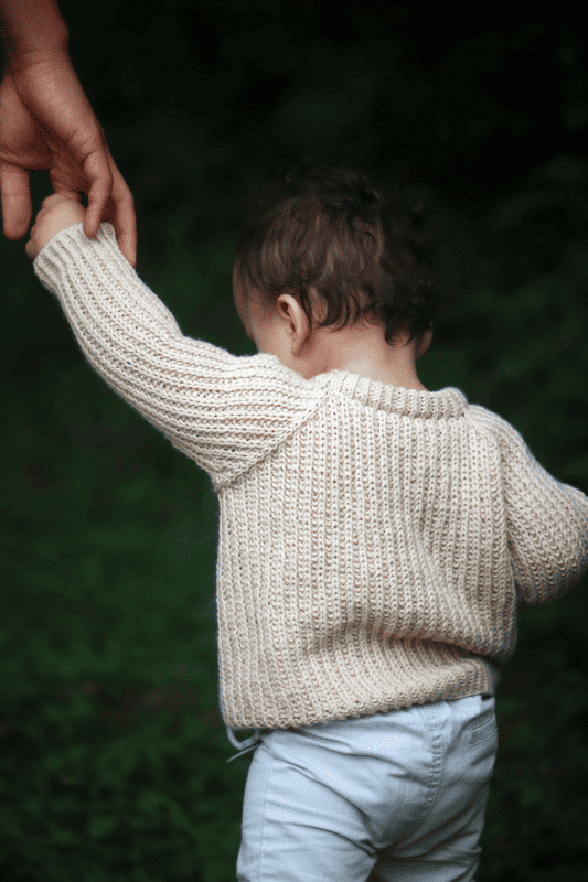 Baby jumper knitting pattern with classic fisherman rib texture in cream wool