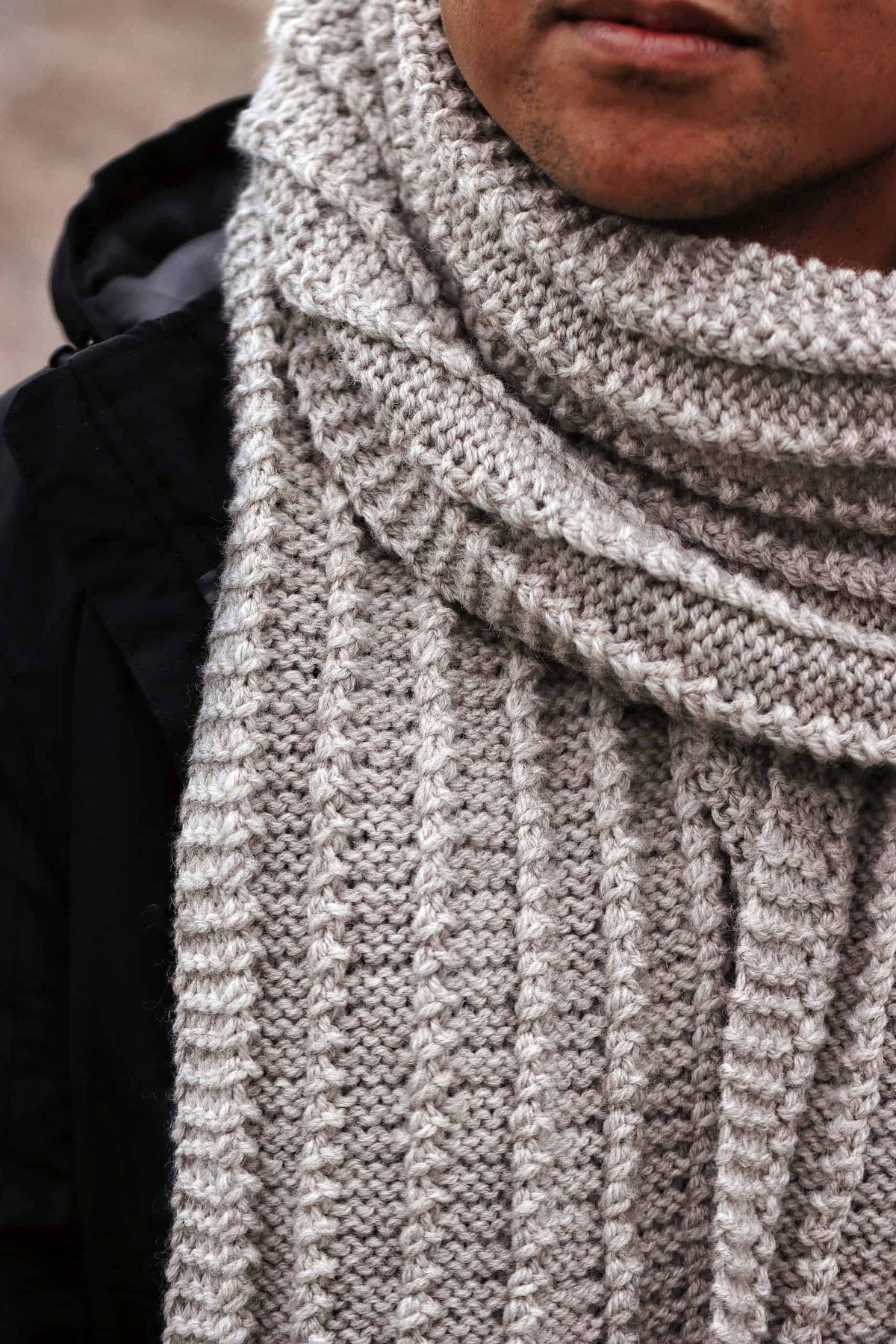Man wearing handknit textured scarf from beginner-friendly knitting pattern