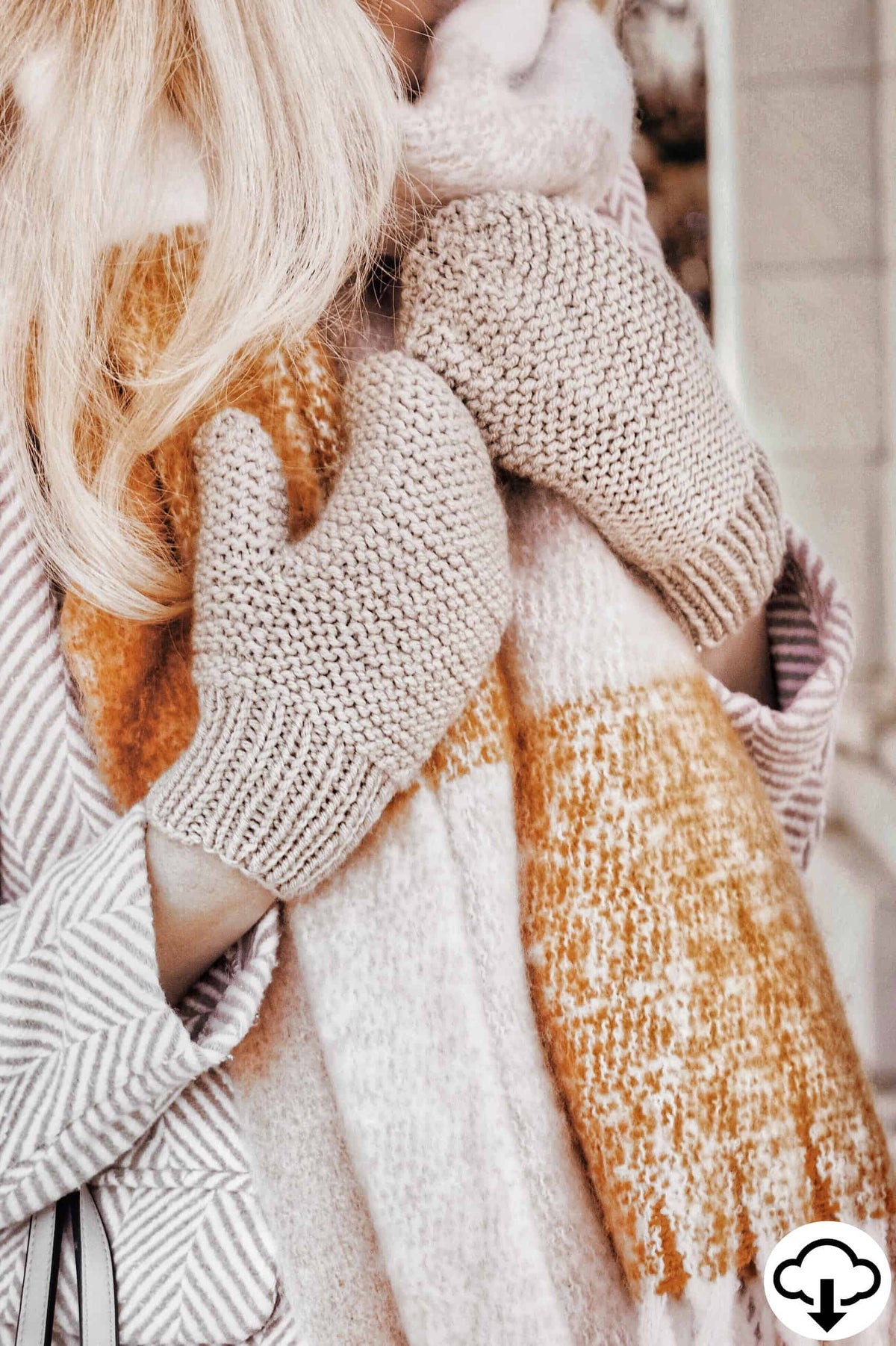 Cream knitted mittens with textured pattern laid on wooden surface - Frostfall Mittens knitting pattern by Darling Jadore