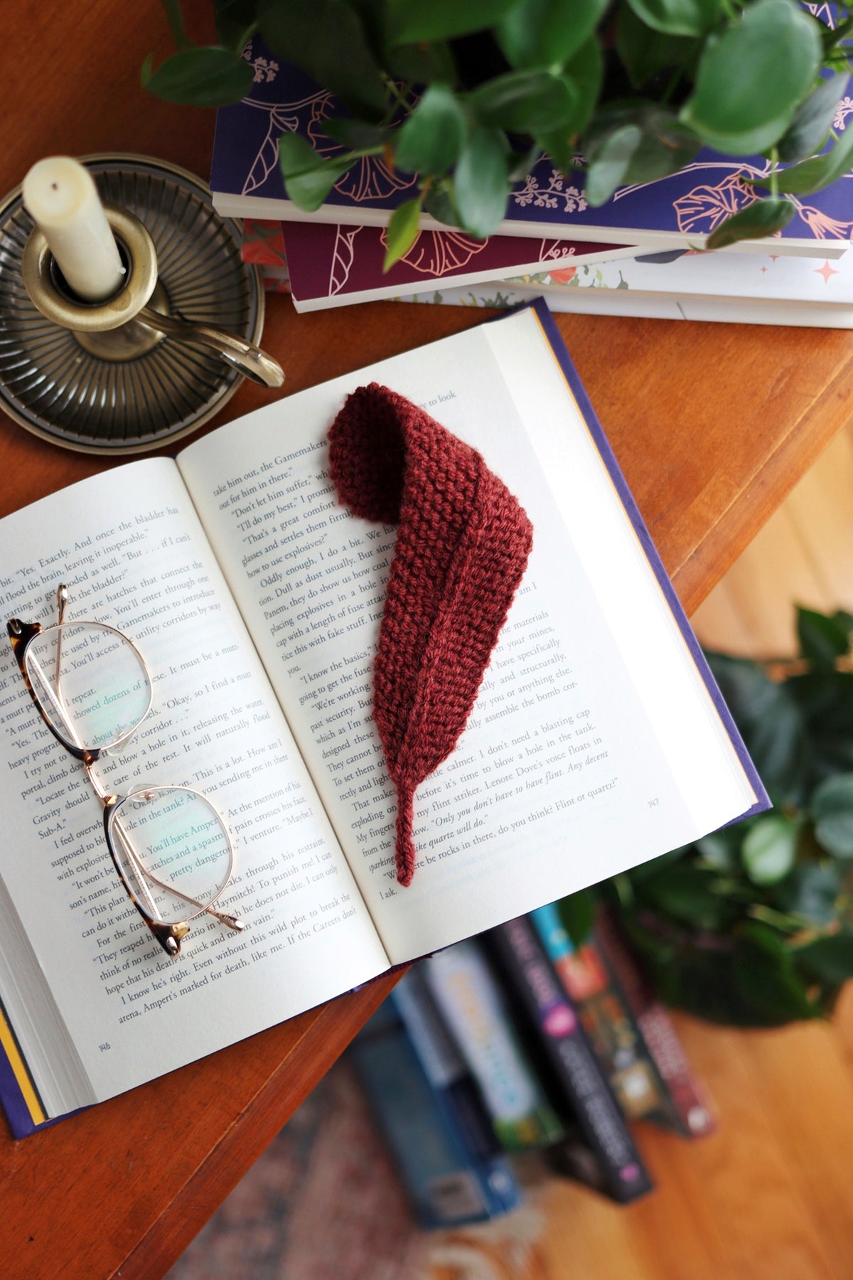 Delicate knitted feather bookmark in cream yarn on open book - beginner knitting pattern by Darling Jadore