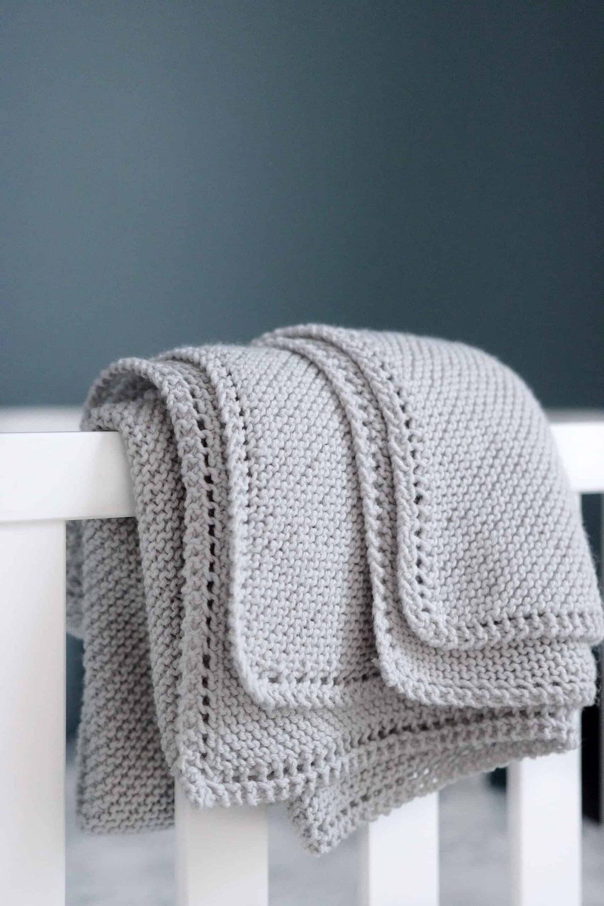 Soft cream receiving blanket knitting pattern with elegant eyelet edge on neutral background