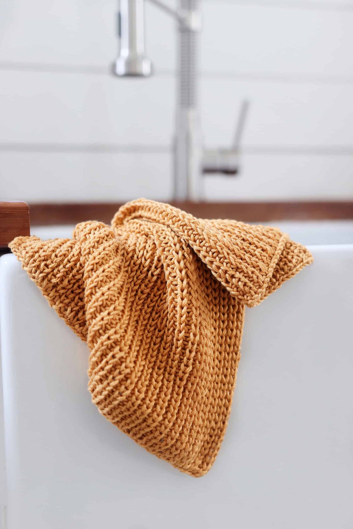 Golden knitted tea towel with rhythmic fisherman's rib pattern perfect for eco-friendly kitchen decor