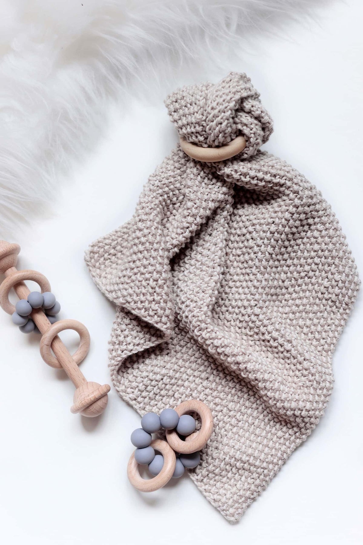 Close up of textured baby lovey knitting pattern with wooden teething ring