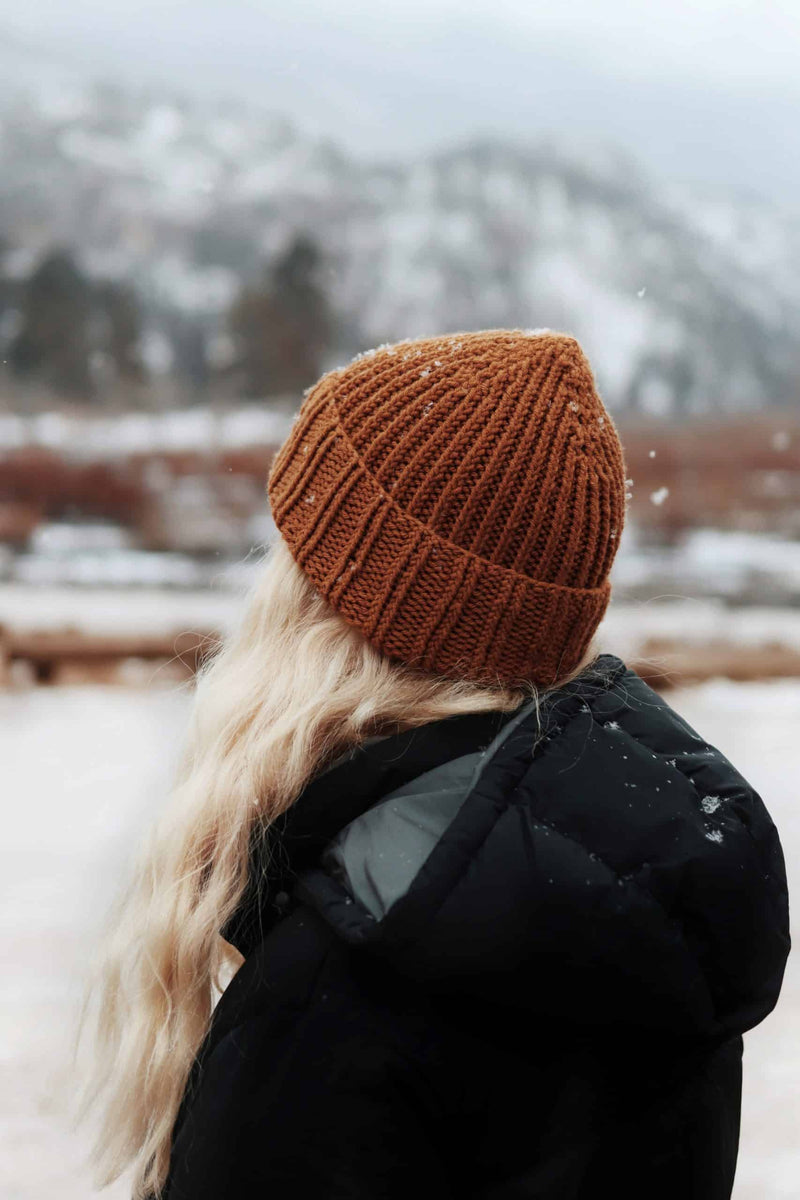Classic ribbed beanie knitting pattern in brown yarn with stretchy texture