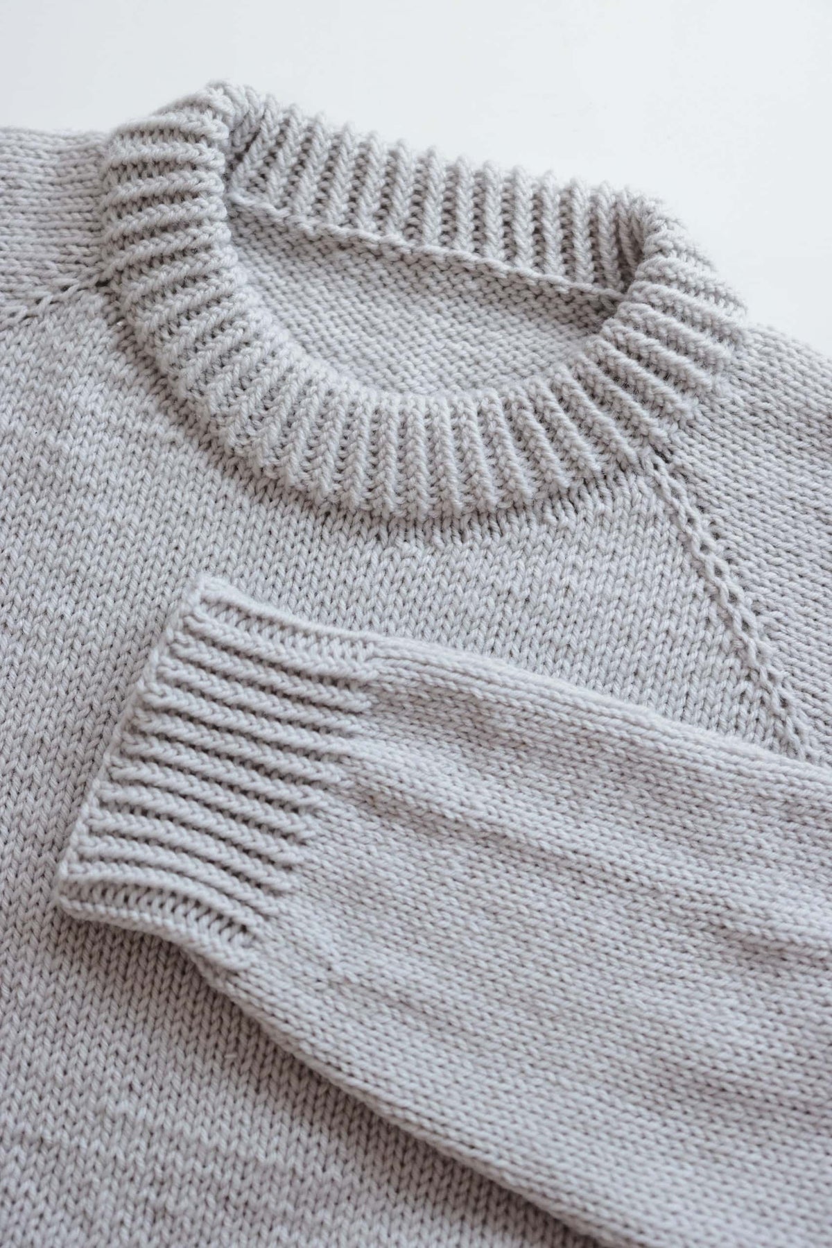 Close-up of Essential Sweater raglan construction showing seamless top-down knitting technique
