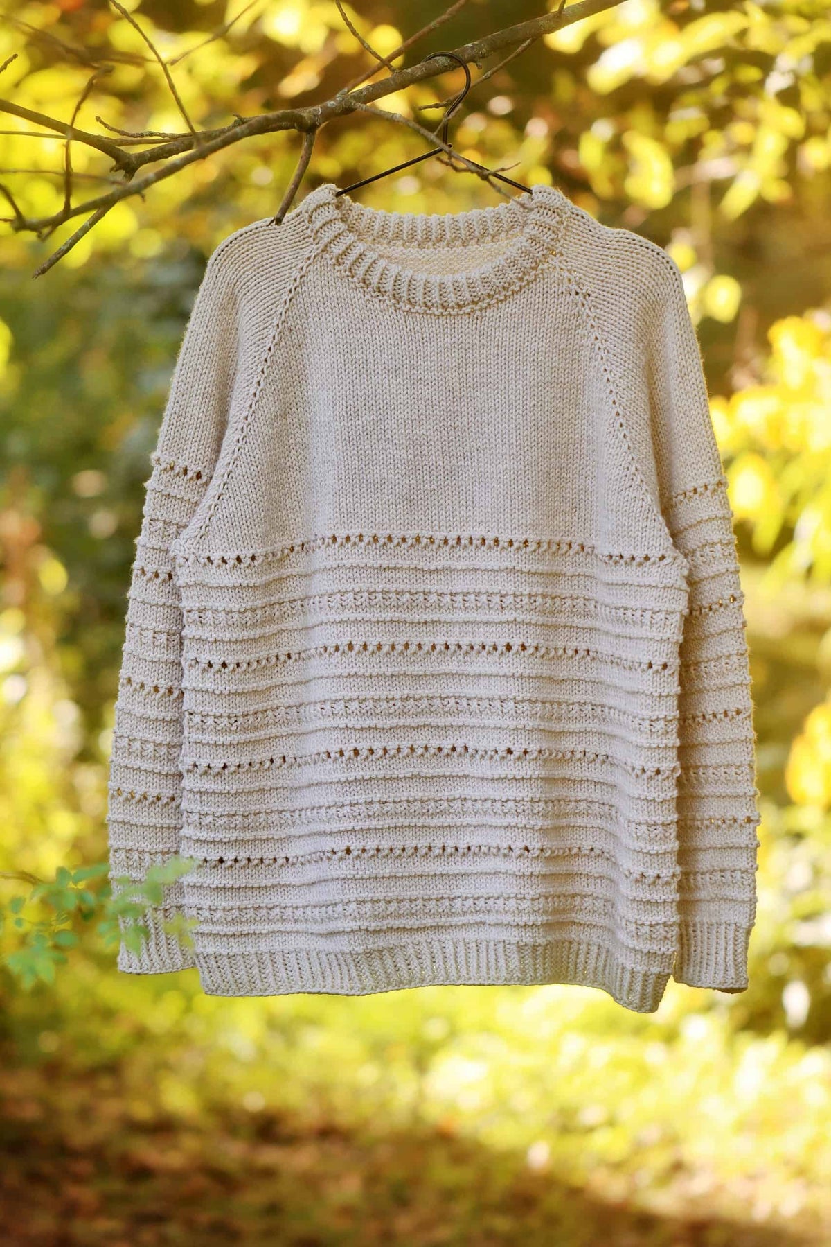 Close-up of textured lace sweater knitting pattern showing eyelet detail and ribbing