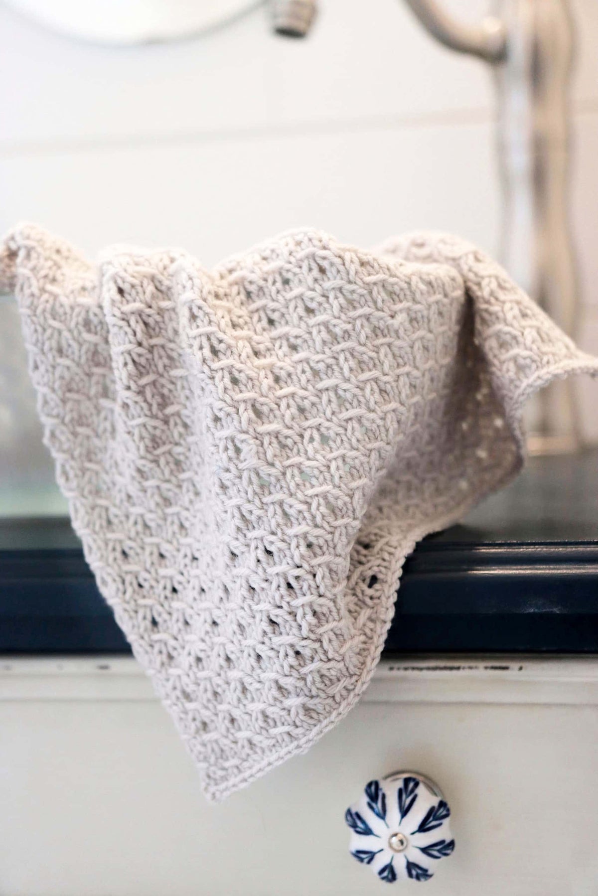 Cream lace knit tea towel with decorative border hanging on wooden rack - Foxberry Towel knitting pattern by Darling Jadore