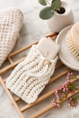 Eco-friendly knit soap saver bag with lacy stitches and drawstring closure holding bar soap