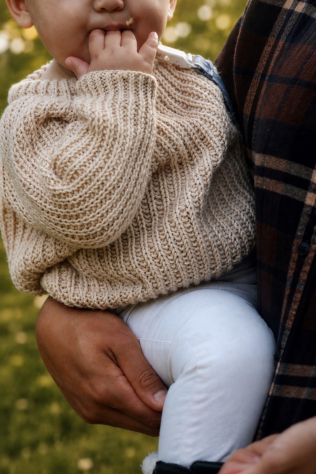 Baby raglan sweater knitting pattern with fisherman rib texture in soft cream yarn